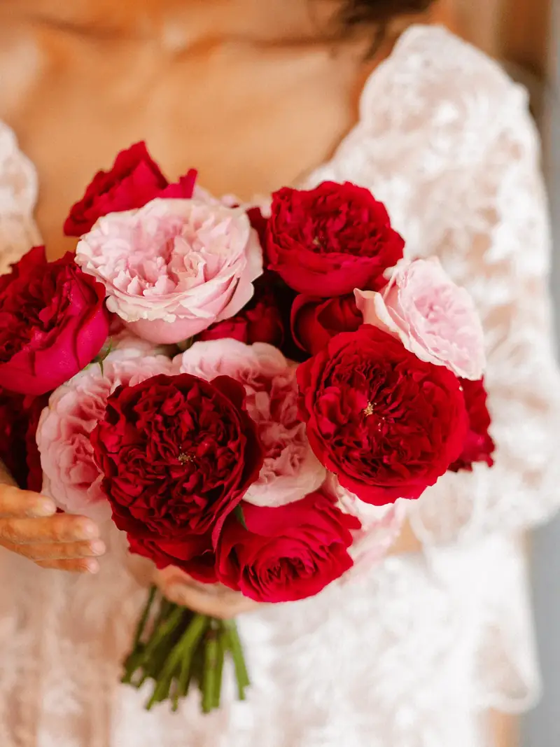 Bride with a bouquet of red and pink roses at an Everards Farm wedding